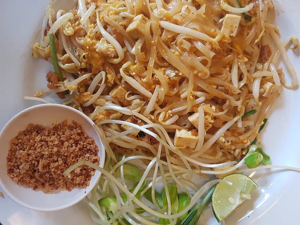 パッタイの実写写真（タイ・チェンマイの屋台/現行型パッタイの完成皿（麺・もやし・ライム・ピーナッツ）。CC0）