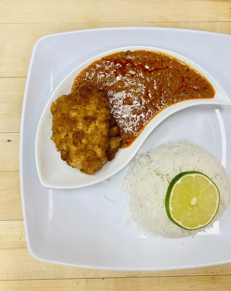 マアフェの実写写真（落花生ソースに鶏肉、白飯とライム添え（鶏はパン粉衣のフライ仕立て＝現代的な調理法）。前回却下（具が見えない／米が無い）の是正＝ソースの質感と具、白飯を明示）