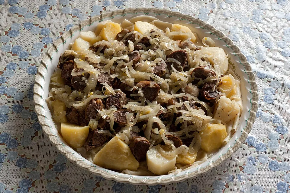 ベシュバルマクの実写写真（カザフ式ベシュバルマク。茹でた肉と平たい小麦麺皮を大皿に盛る現行形。撮影者Igor22121976・CC BY 3.0）