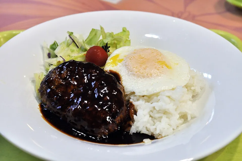 ロコモコの実写写真（ハワイ式ロコモコの現行完成皿。白飯＋グレービーをかけたハンバーグパティ＋目玉焼き（黄身が明瞭に見える）＋サラダ。operator却下理由『黄身が見えない』を満たす差し替え候補（半熟目玉焼きの黄身が上面に露出））