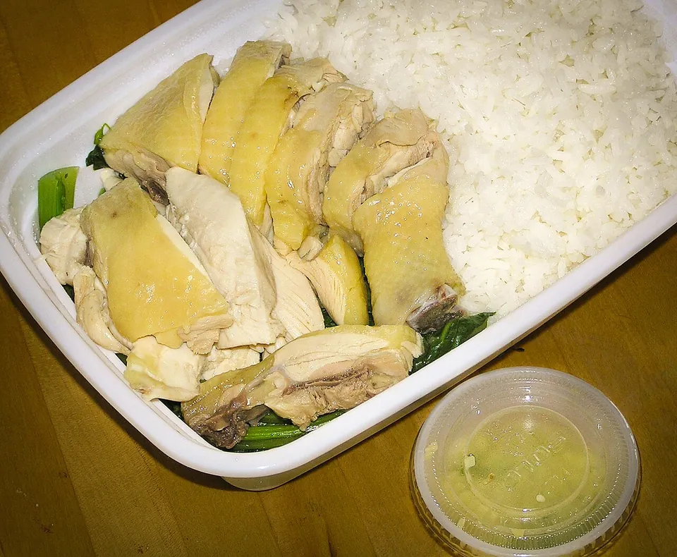 白切鶏の実写写真（広東式白切鶏（白斬雞）＝低温で浸し茹でした鶏を骨付きで切り分けた完成皿。淡黄色の皮・生姜葱ダレ添えで技法（浸し茹で）と広東の焼味/飯店の供膳形が明瞭。青菜と白飯を添えた粤菜の飯プレート形。撮影:Benjwong(PD)）