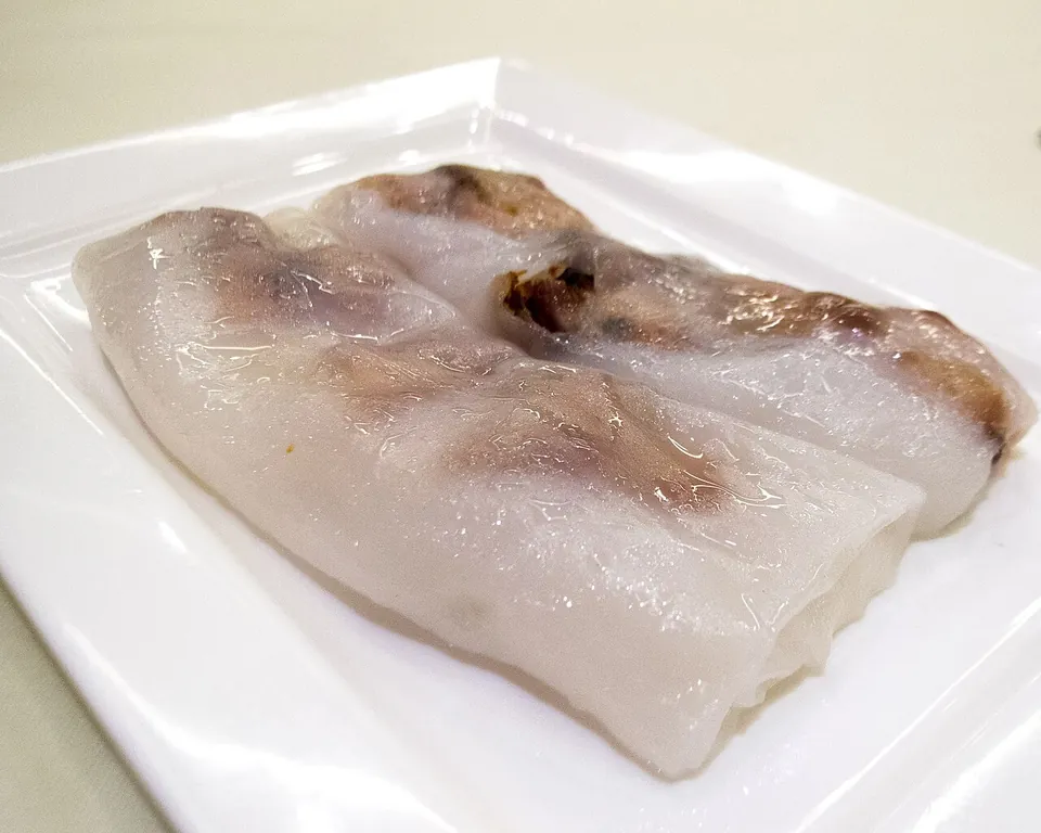 腸粉の実写写真（広東点心の叉燒腸（チャーシュー入り布拉腸）＝腸粉の代表的完成形。米漿を薄く蒸した半透明の粉皮でチャーシューを巻いた広州式布拉腸そのもの。撮影は香港（利苑酒家）だが、腸粉の様式は広東一円で共通で広州の布拉腸を代表する。※本ページの地域は中国・広州（region#157）。豉油（醤油）は皿上では控えめ。）