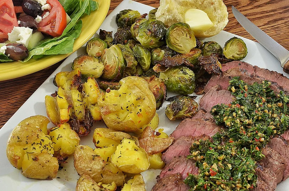 チミチュリの実写写真（アルゼンチンのチミチュリ（現行形）。焼いた牛肉に鮮やかで明るい緑のチミチュリ（パセリ主体＋赤唐辛子フレーク）をたっぷり掛けた、この料理の最も一般的な用途＝焼き肉への添え。前回却下『写真が暗い。もっと鮮やか』を解消＝新鮮で発色の良い緑。起源説は中立に扱い起源譚を演出しない。撮影地=米国）