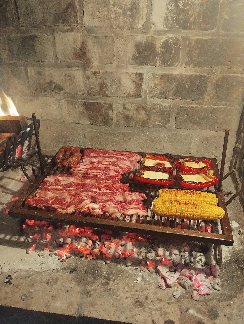 アサードの実写写真（アルゼンチン式アサード（炭火/parrillaで焼く牛肉・ラプラタ地域ガウチョ文化の現行形。焼き場そのものがこの料理の代表的な姿））