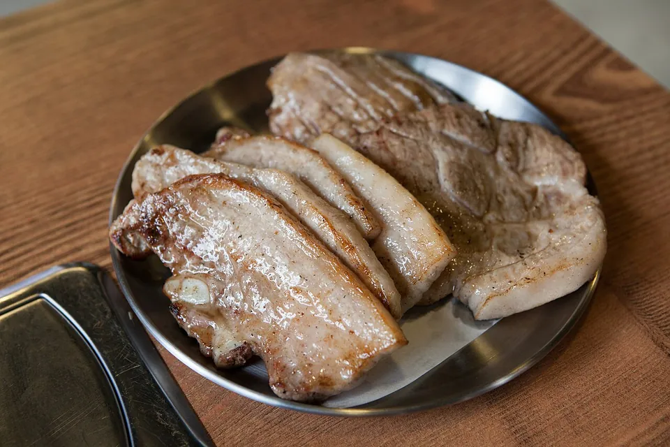 サムギョプサルの実写写真（焼き上げてハサミで切り分けた豚バラ肉（サムギョプサル）。網焼き後の代表的な提供状態。）